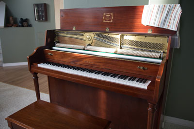 An upright piano with the lid open for cleaning