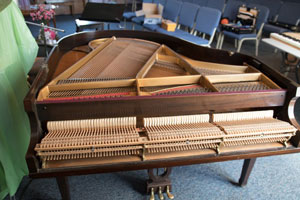 piano tuner Mark Mention with grand piano with lid and keys removed